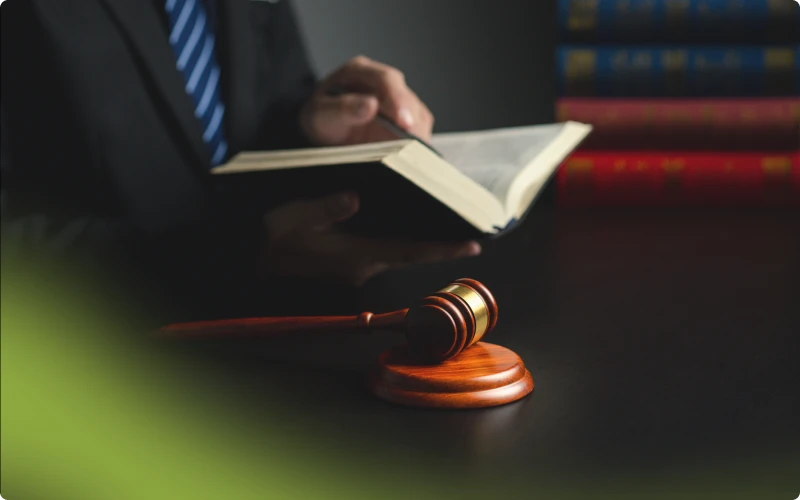 Abogado revisando un libro legal junto a un mazo, representando la defensa legal por prostitución en Pasadena