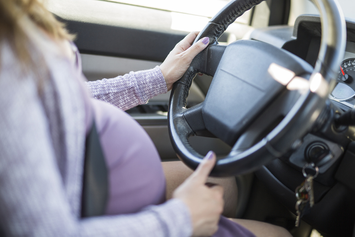A pregnant woman driving a car