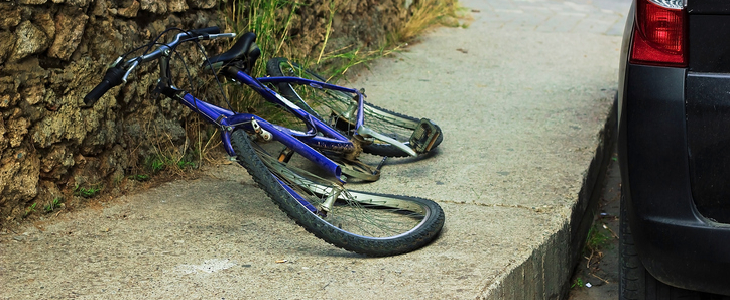 crushed bicycle on the floor with a car next to it