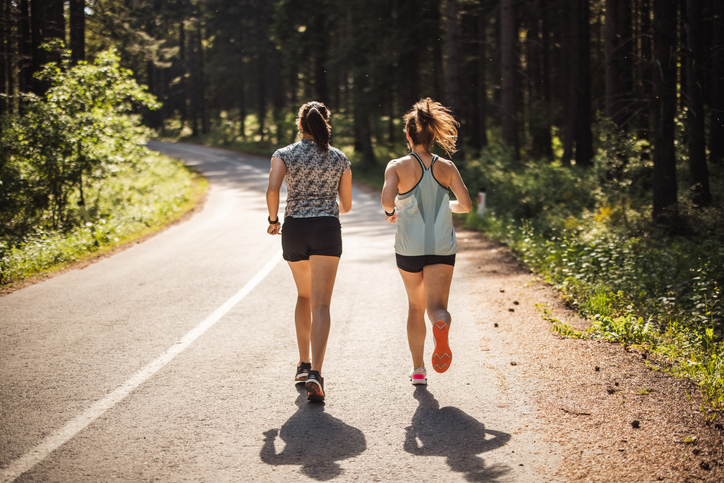 Two joggers running down an empty road
