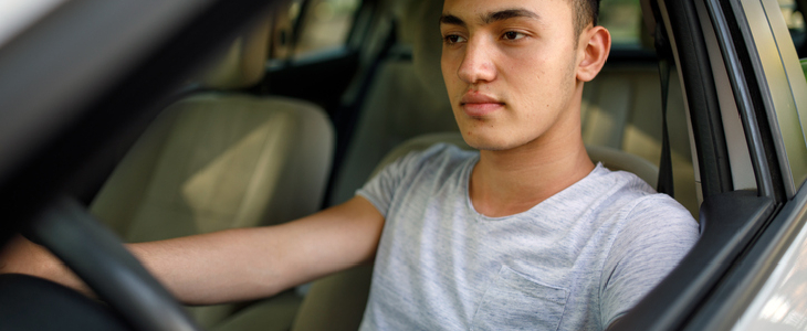 A teenage boy driving a car nervously