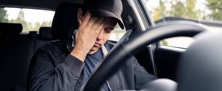 Drowsy driver rubbing his while while on the road