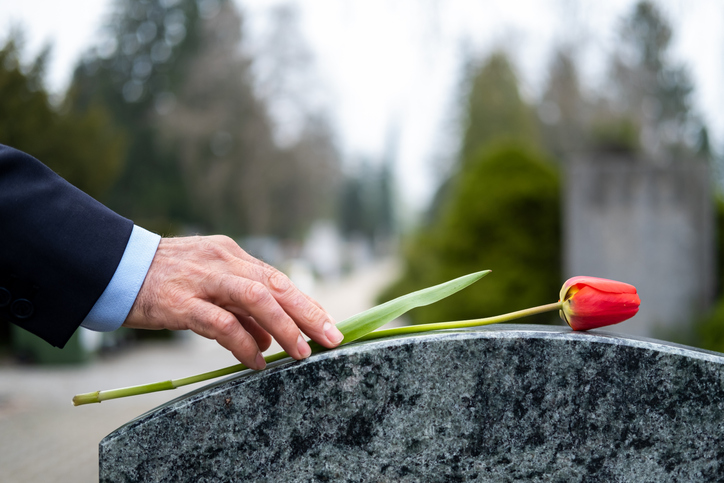 Man putting a tulip on a headstone