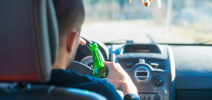A man holding a beer driving drunk