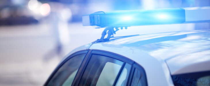 Police car with blue lights on the crime scene in traffic urban environment.