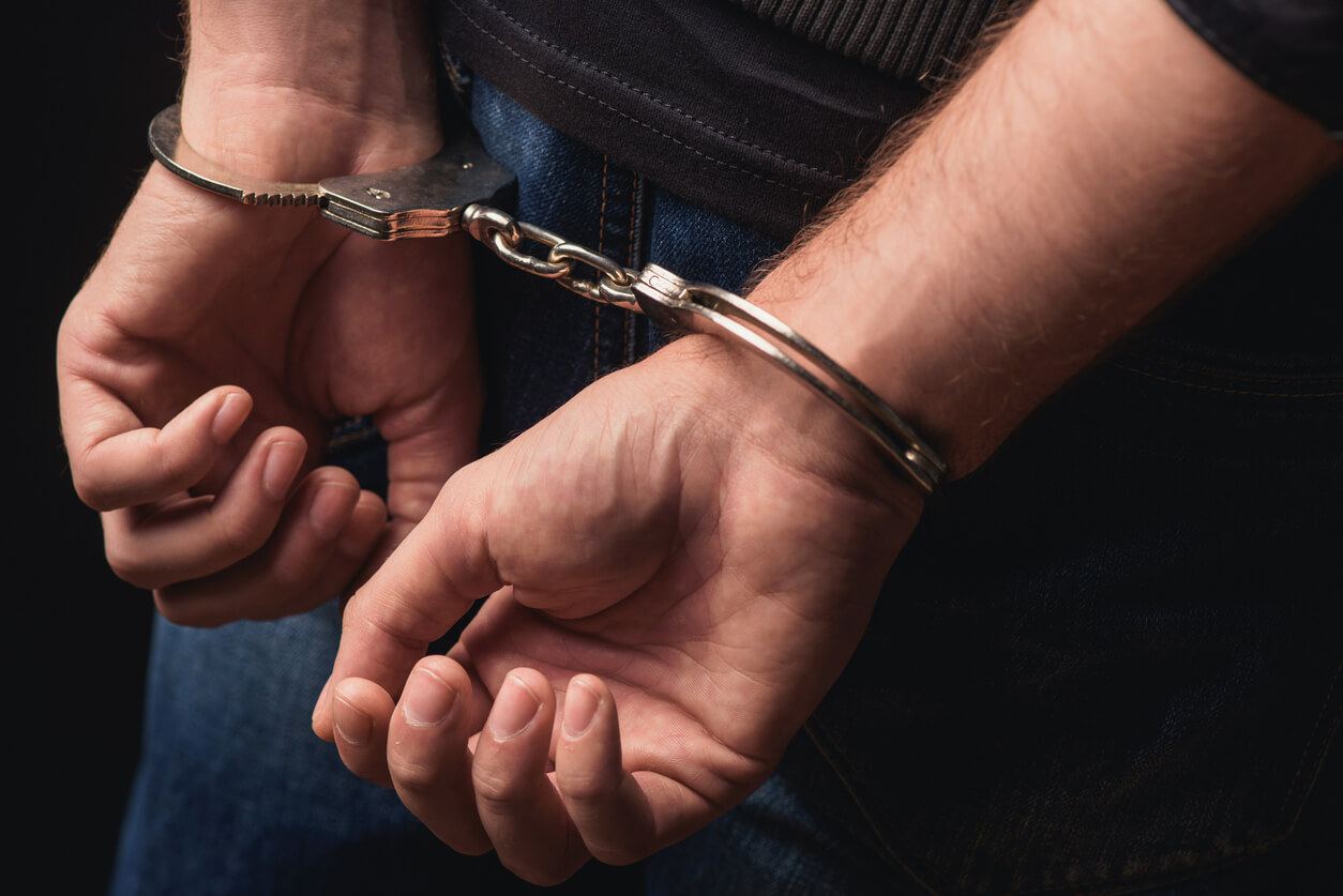 Close up of male hands in handcuffs behind back